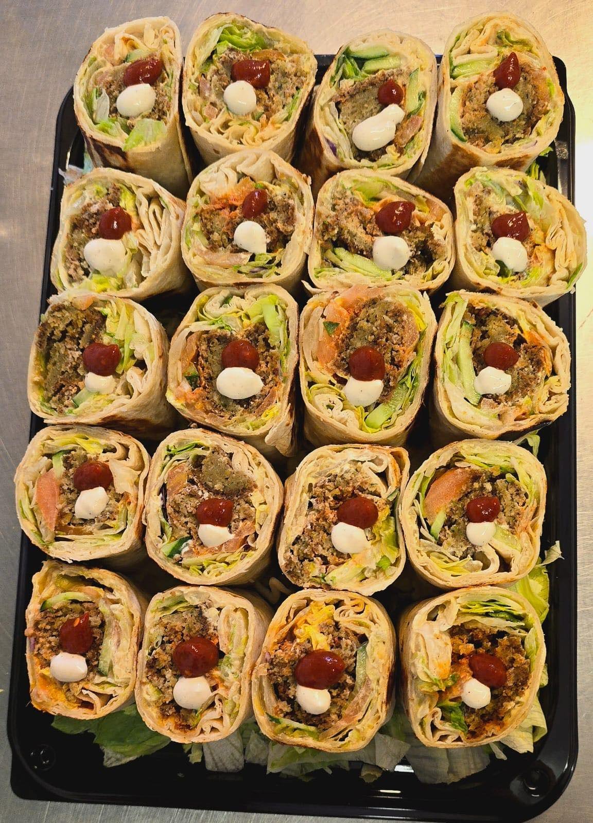 Party tray of sliced falafel and shawarma wraps prepared for a catering order